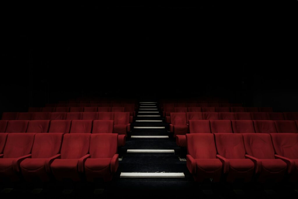 Rows of seats facing a cinema screen in a dark movie theater