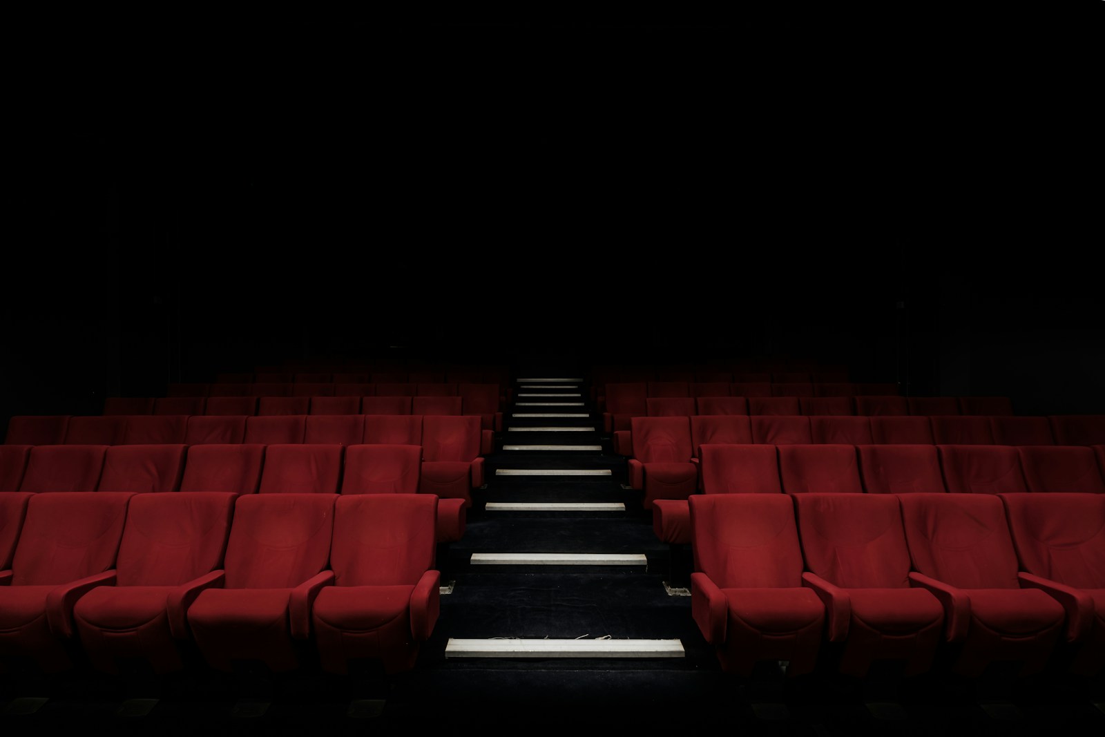 Rows of seats facing a cinema screen in a dark movie theater